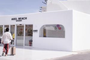 a woman with a suitcase walking out of an apple store at Axel Beach Mykonos - Adults Only in Mikonos