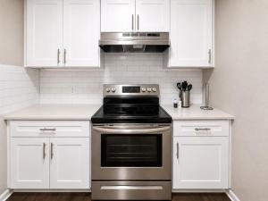 a kitchen with white cabinets and a stainless steel oven at Maple n Main Hoover Modern 2BR Escape 2E in Hoover