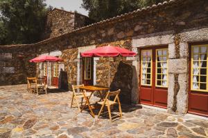 two tables and chairs with red umbrellas in front of a building at Casa De Anquiao - Turismo de Habitação in Ponte de Lima