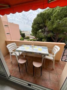 a table and chairs on a balcony with a view at 50 pas de l'Ô in Saint-Cyr-sur-Mer