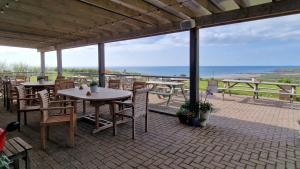a patio with tables and chairs and a view of the ocean at Widdy Bay View in Widemouth Bay