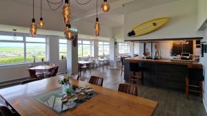 a dining room with a table and a surfboard on the wall at Widdy Bay View in Widemouth Bay