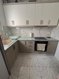 a small kitchen with white cabinets and a sink at Borsh Beach Apartment in Borsh
