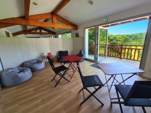 a room with a table and chairs and a balcony at La Noisette Basque - Nuits au verger in Saint-Pée-sur-Nivelle