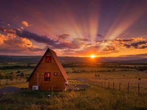 a barn in a field with the sunset in the background at Asureti Horizon Cottage in Asuretʼi