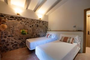 two beds in a room with a stone wall at Can Quel in Canet de Adri +22 photos
