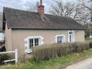 a small house with a brick chimney and white windows at La morvandelle in Limanton