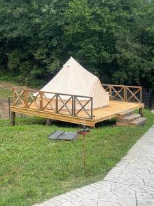a tent sitting on a wooden platform in the grass at Vatra Bunătăților- By The Lake in Proeni