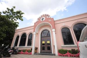 a pink building with a motorcycle parked in front of it at Hotel Rangoli Dharampur in Dharampur