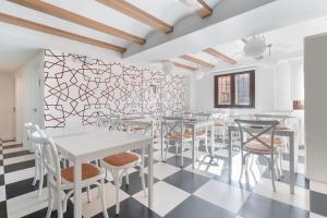 a dining room with white tables and chairs and a geometric wall at OTTIUM Albanuracín in Albarracín +30 photos