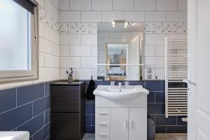 a bathroom with a white sink and blue tiles at Gîte Du Tonnelier - 7min Puy du Fou in Sevremont +22 photos