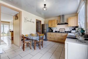 a kitchen with a table with chairs and a refrigerator at Gîte Du Tonnelier - 7min Puy du Fou in Sevremont