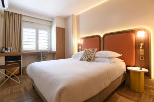 a hotel room with a large white bed and a desk at Hôtel Rotonde Aix-en-Provence centre in Aix-en-Provence +25 photos
