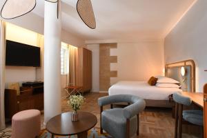 a hotel room with a bed and a table and chairs at Hôtel Rotonde Aix-en-Provence centre in Aix-en-Provence