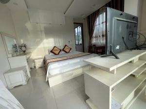 a white bedroom with a large bed and a tv at Anh Duong in Lục Yên