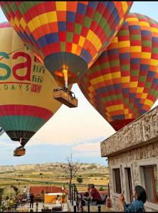 two colorful hot air balloons flying over a building at Süleyman Cappadocia - Hot Air Balloon View in Göreme