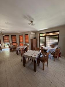 a dining room with tables and chairs and windows at Yuliya Guest House in Sapareva Banya