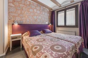 a bedroom with a large bed with a purple headboard at OTTIUM Albanuracín in Albarracín