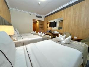a hotel room with two beds and a television at Zowar Alalami Hotel - فندق زوار العالمي in Medina