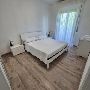 a bedroom with a white bed and a wooden floor at Appartamento Scossicci in Porto Recanati