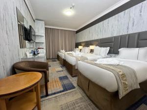 a hotel room with four beds and a table at Zowar Alalami Hotel - فندق زوار العالمي in Medina +11 photos