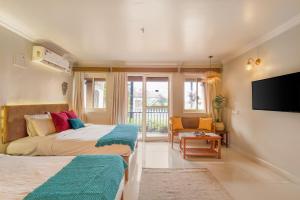 a bedroom with two beds and a flat screen tv at Raposo Resorts in Vagator +63 photos