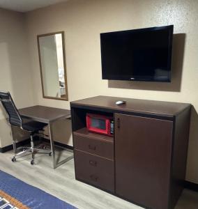 a room with a desk and a television on a wall at Villa West Inn in Odessa