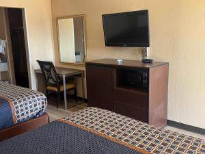 a hotel room with a bed and a flat screen tv at Villa West Inn in Odessa +36 photos