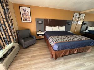 a hotel room with a bed and a chair at Villa West Inn in Odessa