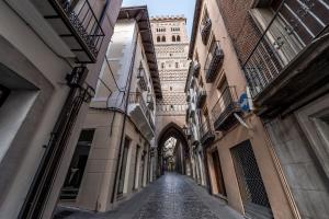 an alley with a clock tower in the distance at La Torre Boutique Apartamentos in Teruel
