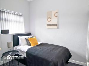 a bedroom with a bed with an orange pillow on it at Comfy 2-Bedroom Family & Contractor Home in Bolton with Free Wi-Fi and Street Parking By North West Accommodation in Bolton