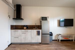 a kitchen with a refrigerator and a tv on the wall at Work and Stay in Maasbree
