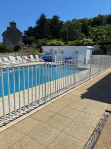 a fence next to a swimming pool with chairs at MAISON 6 pers belle vue mer PISCINE, plage à 40 m in Trévou-Tréguignec