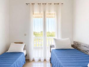 two beds in a room with a window at Cretan Nature Stone Apartment in Ayiás Filakaí