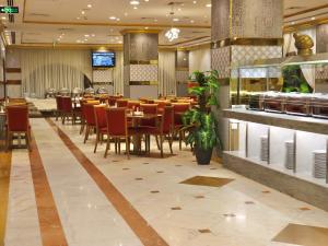 a dining room with tables and chairs in a restaurant at Zowar Alalami Hotel - فندق زوار العالمي in Medina