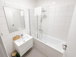 a white bathroom with a sink and a tub and a shower at Aparthotel Olympland in Trutnov +30 photos