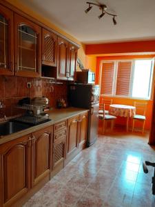 a kitchen with wooden cabinets and a sink and a refrigerator at Апартаменти и стаи Анхиало in Pomorie