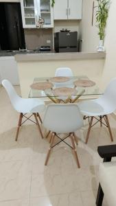 a glass table with four white chairs in a kitchen at Katty House in Santa Bárbara de Samaná