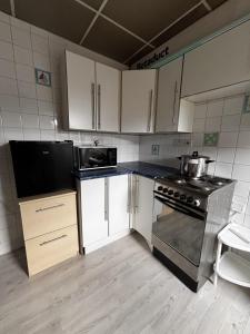 a kitchen with white cabinets and a stove top oven at Stylish Studio with SuperKing Bed in Stonewood