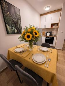 a dining room table with a vase of sunflowers on it at Bo Apartment in Bečići +2 photos