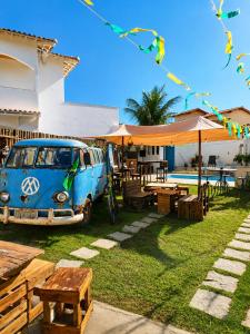 a blue van parked in a yard with tables and umbrellas at Piratas Guest Rooms II in Búzios