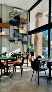 a restaurant with tables and chairs and a large window at Hotel Lieto in Poços de Caldas