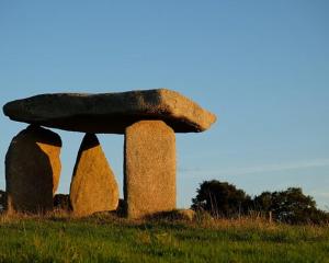 a stone structure in a field with grass at Sunny Cottage in Camborne
