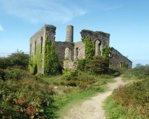 an old stone building on a hill with a dirt road at Sunny Cottage in Camborne
