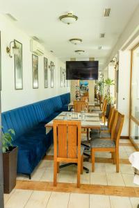 a restaurant with a blue couch and tables and chairs at Hotel Trezor in Varna City