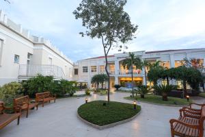a courtyard with benches and a tree in front of a building at Grande Hotel Águas da Prata in Águas da Prata