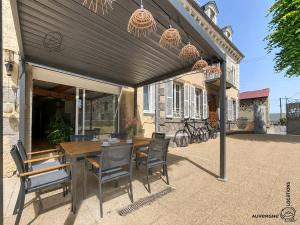 a patio with a wooden table and chairs at L'Hirondelle des Sarments in Montaigut-le-Blanc