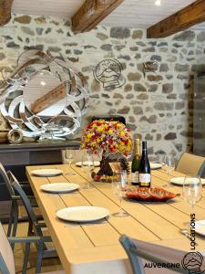 a wooden table with wine glasses and flowers on it at L'Hirondelle des Sarments in Montaigut-le-Blanc