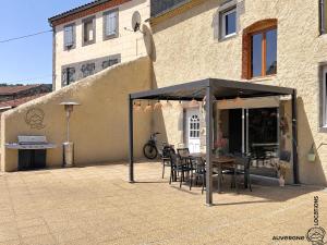 a patio with a table and chairs under a canopy at L'Hirondelle des Sarments in Montaigut-le-Blanc +13 photos