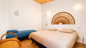 a bedroom with a bed and a blue chair at L'Hirondelle des Sarments in Montaigut-le-Blanc